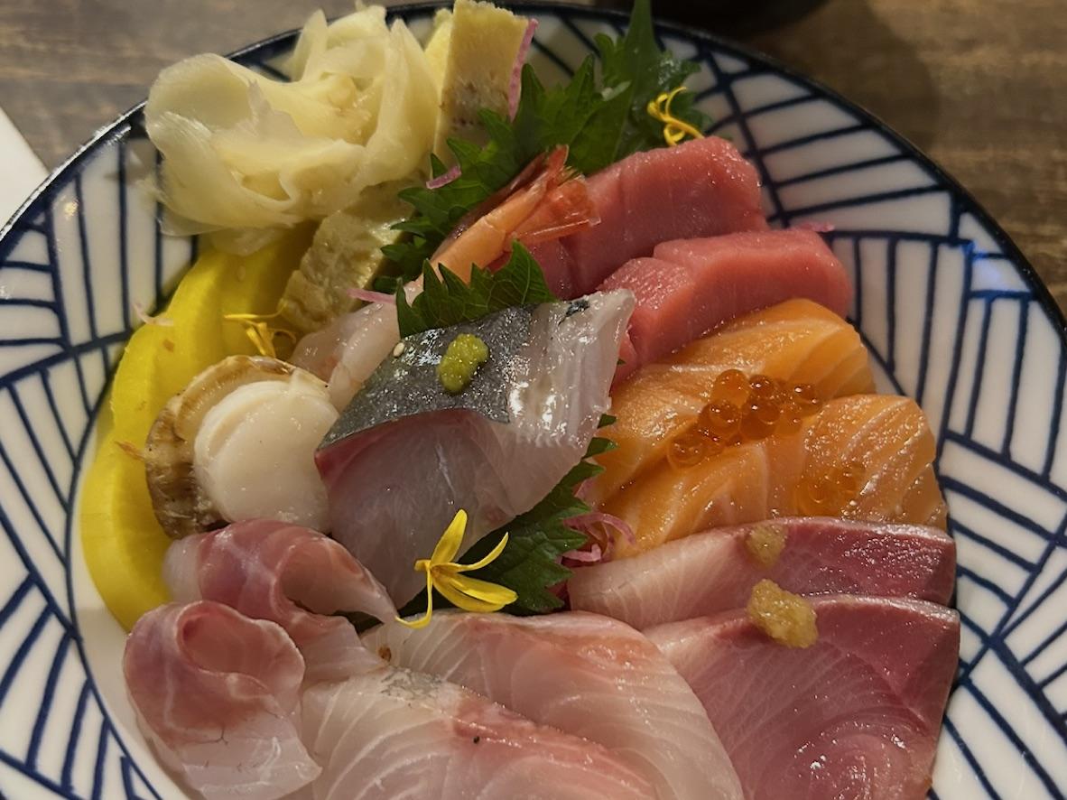Chirashi sushi bowl with assorted sashimi, shrimp, tamago, and pickles over rice