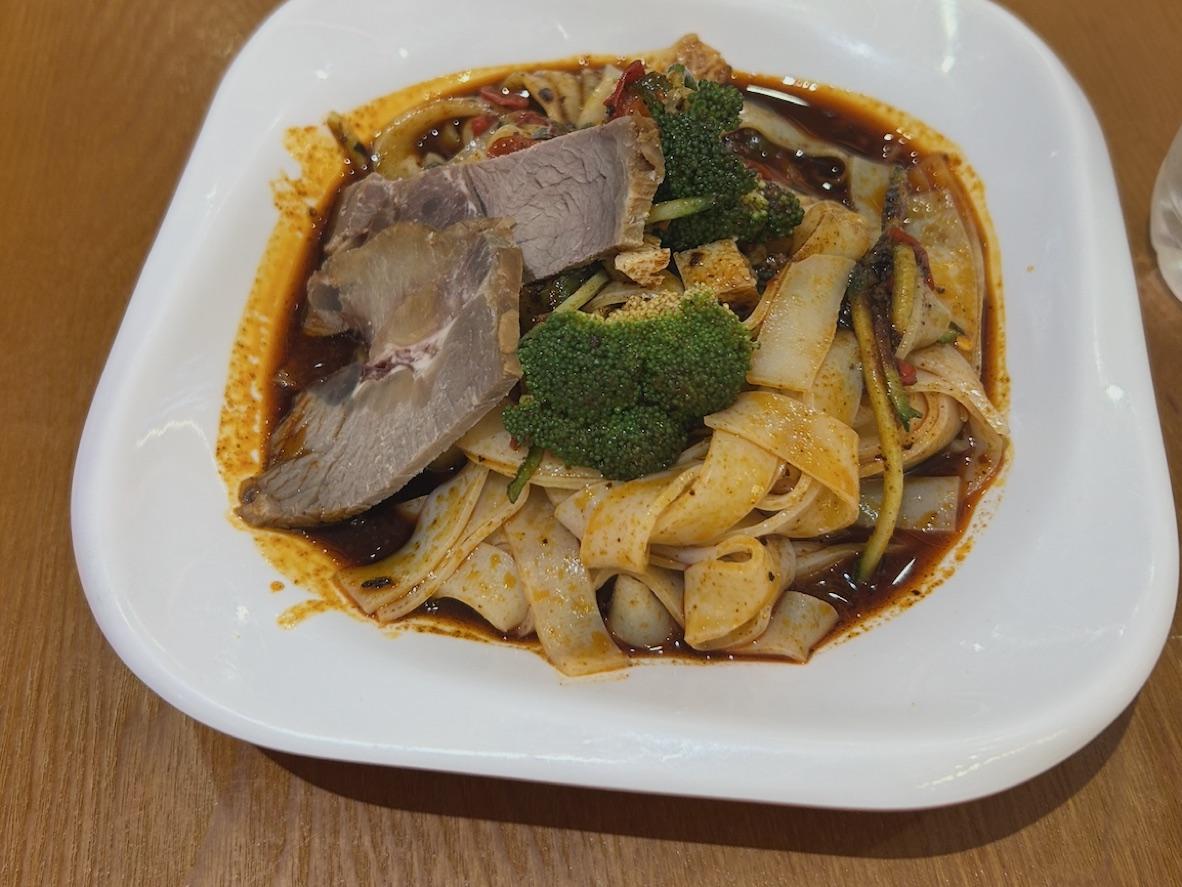 Wide liang pi noodles with sliced beef, broccoli, and spicy red chile sauce