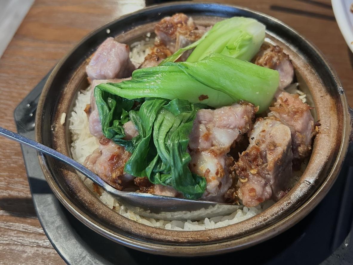 Pork rib claypot rice with bok choy in a black clay pot