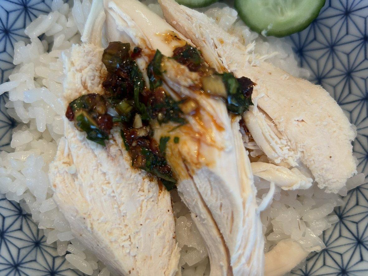 Sliced rotisserie chicken over rice with cucumbers and chili-crisp sauce