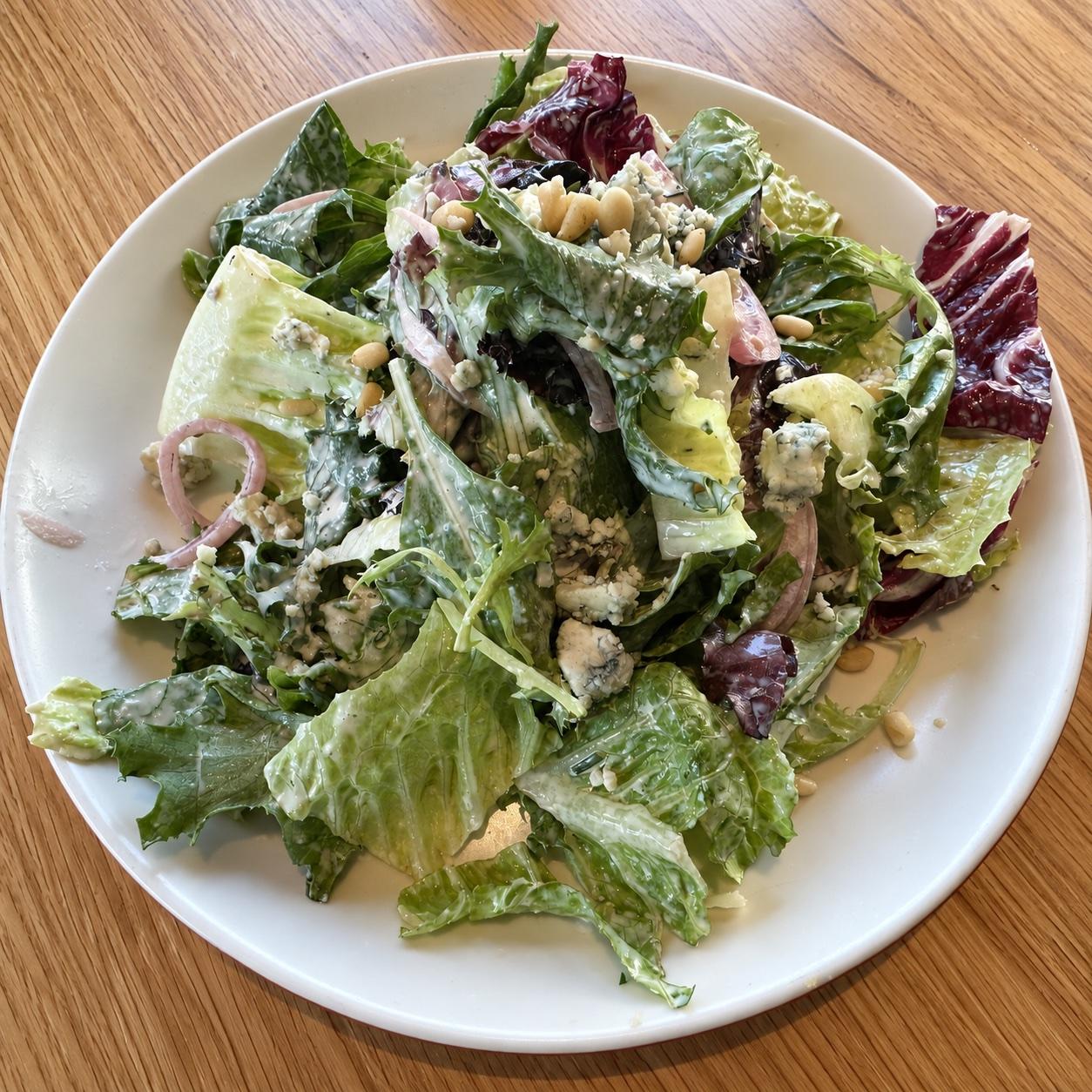 Mixed green salad with gorgonzola, pine nuts, tomatoes, and pickled red onion